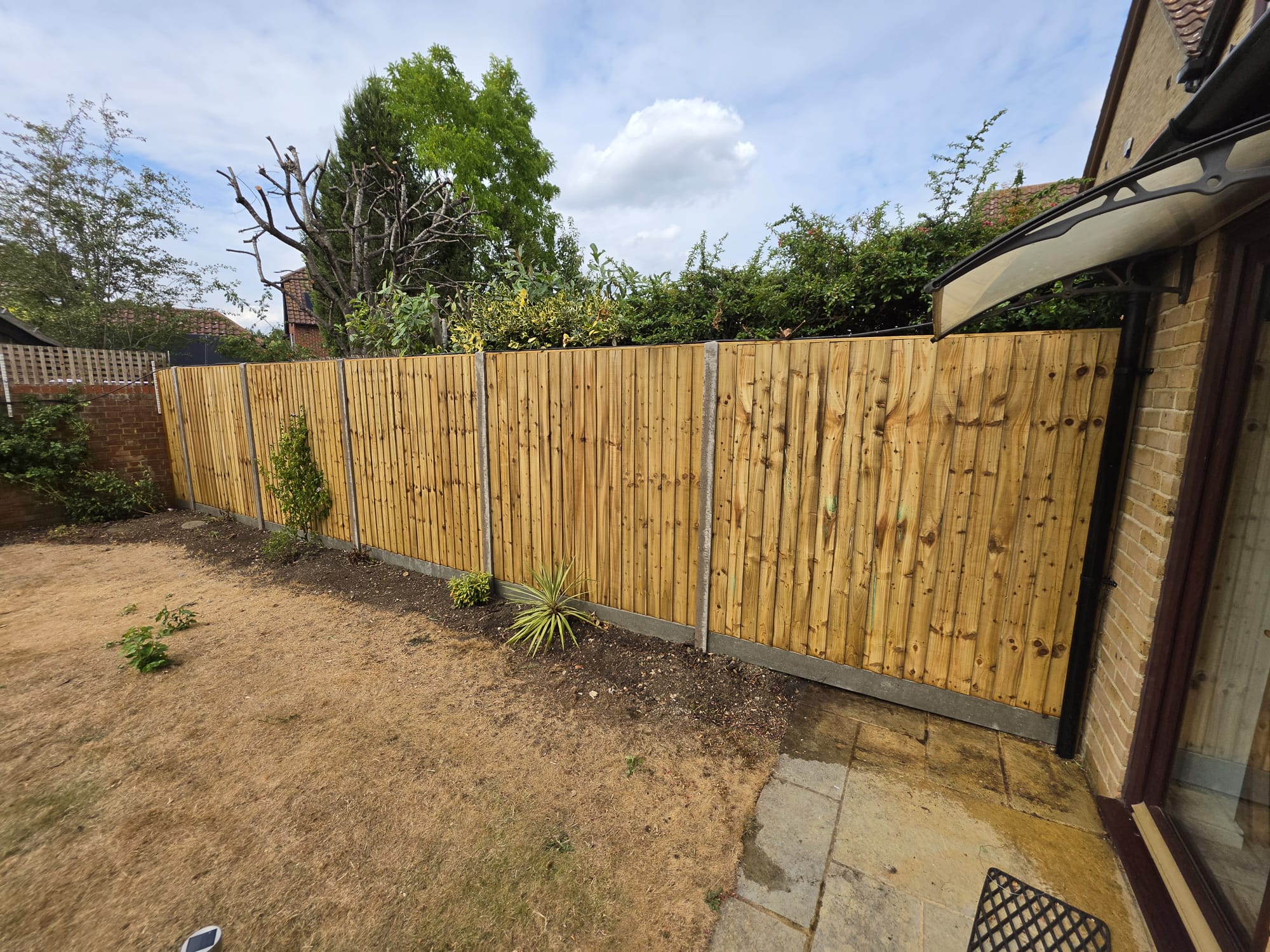 New golden closeboard timber fence panels with concrete posts and gravel boards