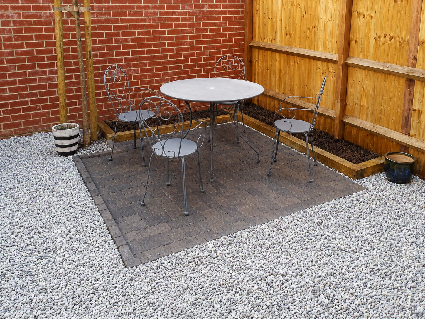Block-paved patio seating area bordered by gravel and fencing