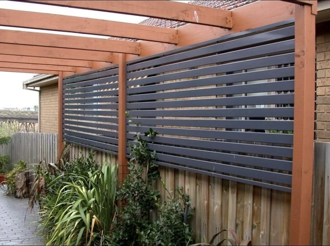 Modern slatted privacy screen fencing above a garden pergola